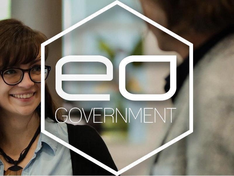 Zwei Personen im Gespräch, darüberliegend das Logo des Projektes E- und Open Government